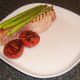 Griddled asparagus and tomato are plated with sweetcure bacon steak