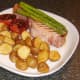 Griddled bacon steak with asparagus and roast potatoes is served