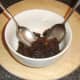 Christmas pudding is shaped between two dessert spoons for plating