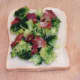 Bacon and broccoli are laid on uintoasted side of bread