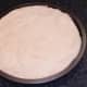 Pizza dough is fitted in to greased tin