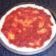Tomato sauce is smoothed over pizza dough