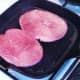 Oiled gammon steaks are added to hot griddle pan