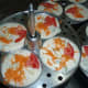 Rava idli batter with carrot, cashew nuts, and tomato topping.