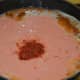 Step three: Add tomato and cashew nut paste to the pan. Add Kashmiri chili powder.