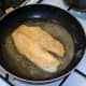 Tilapia fillet is turned to fry on second side