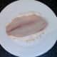 Tilapia fillet is patted in seasoned flour