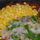 Step eight: Add cooked corn, onions, and capsicum. Stir-fry for a minute.