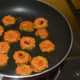Step five: Add 1 teaspoon of oil on a hot non-stick pan. Place the batter-coated bitter gourd slices one by one as shown. Add a few drops of oil on them.