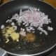 Step two: Heat oil in a deep-bottomed pan. Add mustard seeds. Let them pop up. Add asafoetida powder, minced ginger, and garlic. Throw in chopped onions.