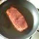 Pork steak is added to frying pan