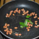 Step two: Heat oil in a deep-bottomed pan. Add mustard seeds, peanuts, and curry leaves. Saute till mustard crackles.