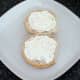 Cream cheese is spread on bread roll