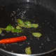 Step three: Heat a tablespoon of oil in a deep-bottomed pan. Throw in mustard seeds. Let them crackle. Add dry red chili and curry leaves. Saute for a while.