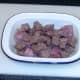Steak and venison sausage is arranged in pie dish