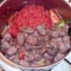 Canned tomatoes are added to pot with browned sausages and liver