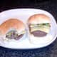 Biting in to cheeseburger with fried sprouts and onion
