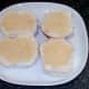 Mustard is spread on cut bread rolls