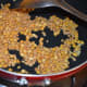 Saut&eacute; split chickpea (gram dal) and white lentil (urad dal) in oil until they get lightly golden brown.
