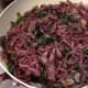 Skillet with pho noodles that have been soaked in red wine, with sauteed greens and onions