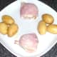 Bacon wrapped mozzarella stuffed garlic mushrooms and buttered new potatoes are plated