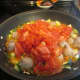 Peeled, and chopped tomatoes being added to the pan.