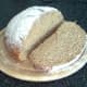 A thick slice is cut from a wheat, spelt and rye loaf