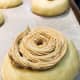 Use a piping bag to pipe the coffee topping on every dough ball. Use a spiral motion.