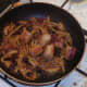 Chopped cooked sausages are added to pan with spiced onion and tomatoes