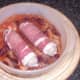 Bacon wrapped chicken sausages are laid on spicy beans for casseroling