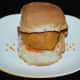 Slit a pav bun horizontally but do not cut all the way through. Spread garlic chutney powder in the slit and then place a potato vada inside.