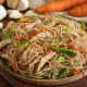 Bihon guisado: Thin rice noodles cooked in a wok with soy sauce, vegetables, and meat.