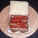 Tomato sauce is spooned on to sausages