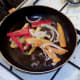 Peppers and onion are flash fried while potatoes drain