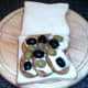 Halved olives are arranged over melted goats cheese and potatoes
