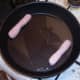 Sausages are added to heated oil in frying pan