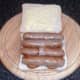 Halved sausages are laid on fried potatoes