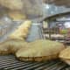 Pita bread coming down the conveyor belt inside of the store