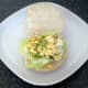 Mashed egg is spread out over lettuce bed
