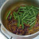 Green beans are added to spiced onions.