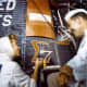 Wally Schirra observes as Cece Bibby paints the Sigma 7 logo. Photo courtesy of NASA.