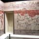 A typical room in the city of Akrotiri with brightly-painted frescoes: two adolescent boys boxing on one wall, a pair of goats dancing in a stylized landscape on the other.