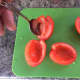 Using a spoon to de-seed the plum tomatoes