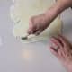 Begin by slicing off the jagged edge of the dough and discarding that back to the bowl for future use. Now you have a beginning edge that you can follow for the rest of your cuts.