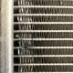 Rock damage to an AC condenser. Each horizontal line is a small tube which carries freon, and the the vertical loops that look like corrugated cardboard are the cooling fins that cool the freon. 