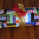 Rolling the quilt and wrapping it with a ribbon will show the fabric, but the quilt pattern will likely still be a mystery.