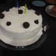 A cake with vanilla frosting and simple chocolate embellishments.