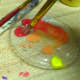 Mixing red and yellow in the paint tray.