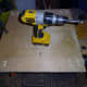 Holes drilled in the base, and through the scrap wood, to fix the wheels