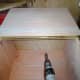 After drilling pilot holes, the piano hinge is screwed into place